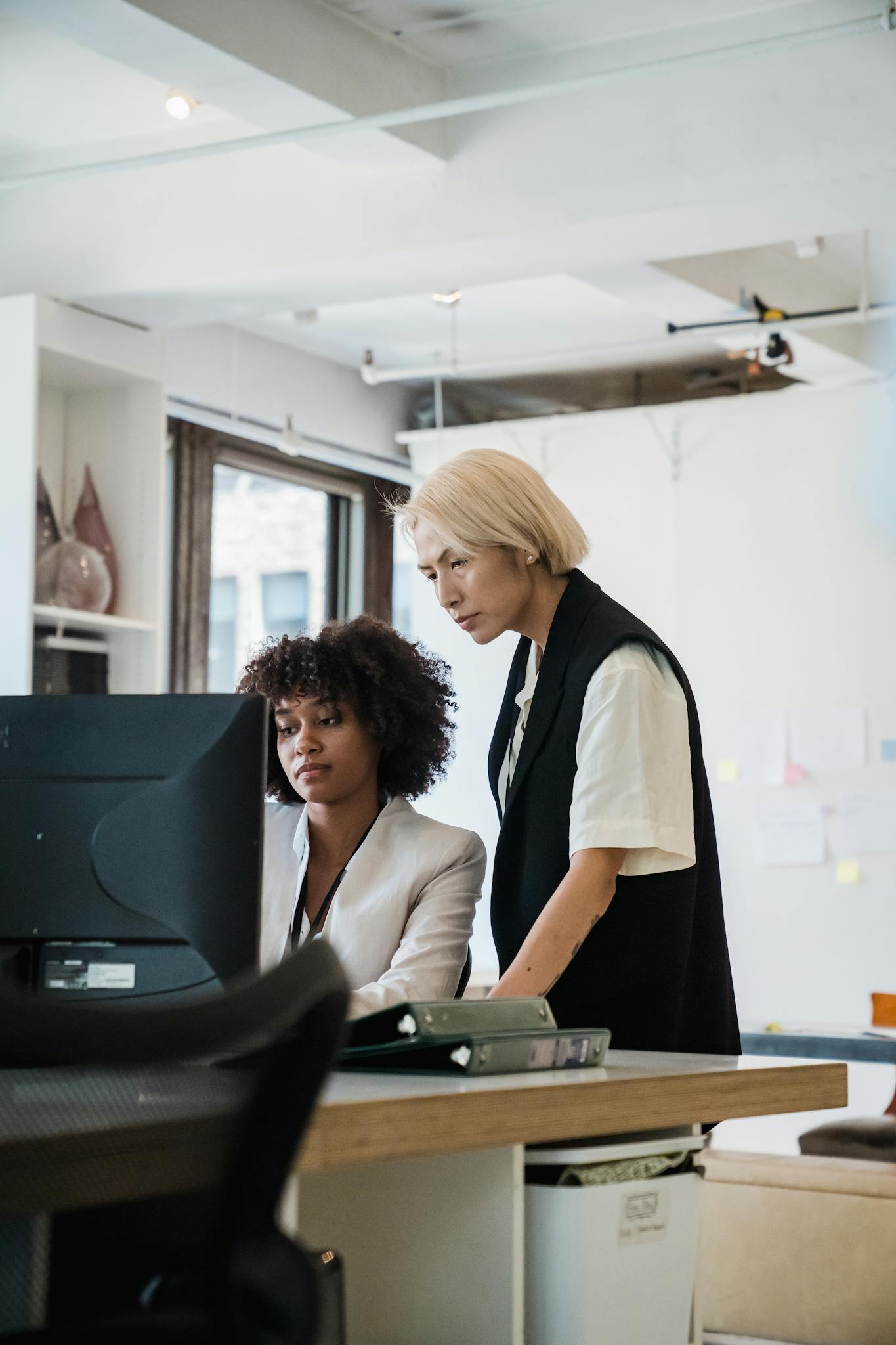 Two employees collaborating at a desk in a bright, modern office environment.