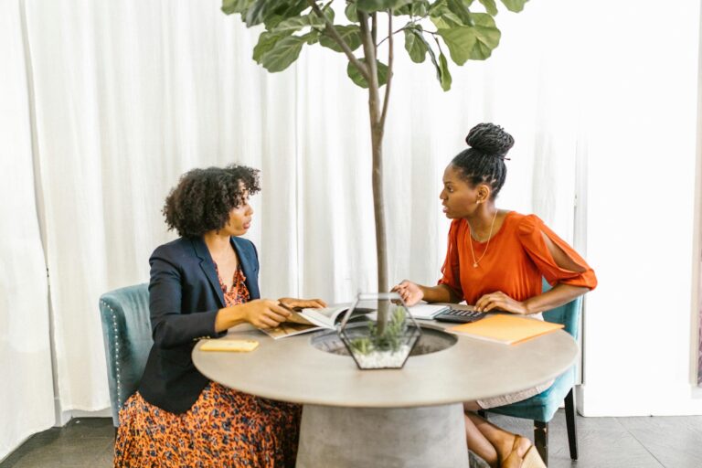 Two women engaged in a business discussion in a modern office setting.